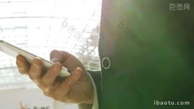 一个商人在明亮的阳光下使用智能手机打字短信或玩游戏的特写镜头